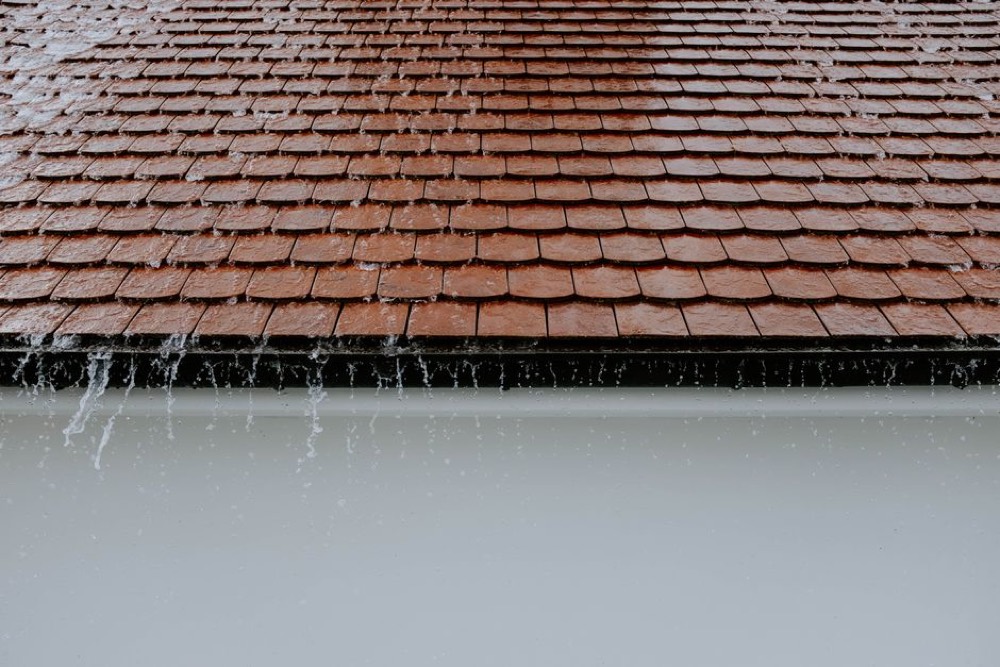 Eau de pluie qui s'écoule d'un toit en tuiles vers la gouttière